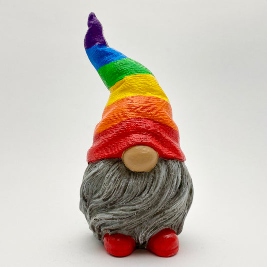 A small hand painted gonk statue with a rainbow striped Hat, a grey beard and red Shoes. Front view.