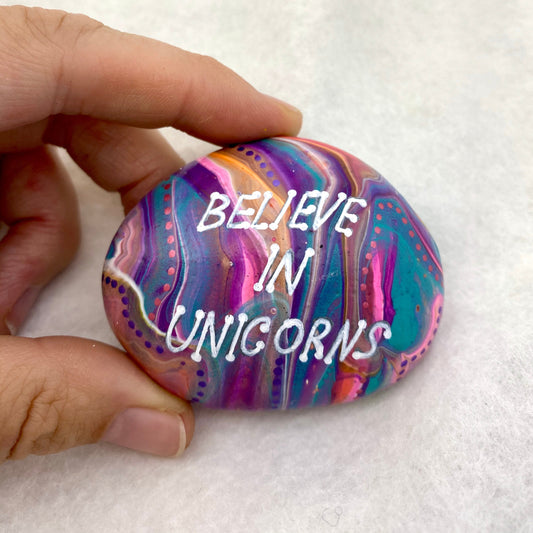 Colourful Hand painted Stone with the words Believe in Unicorns