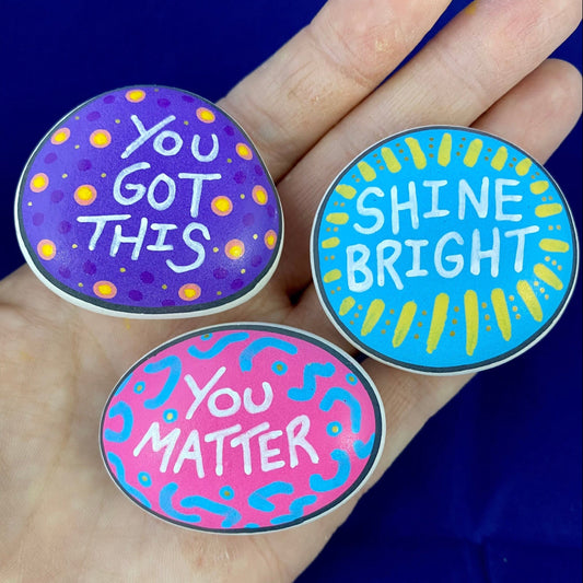 3 Colourful Hand painted pebbles with the words You Got This, Shine Bright and You Matter written on