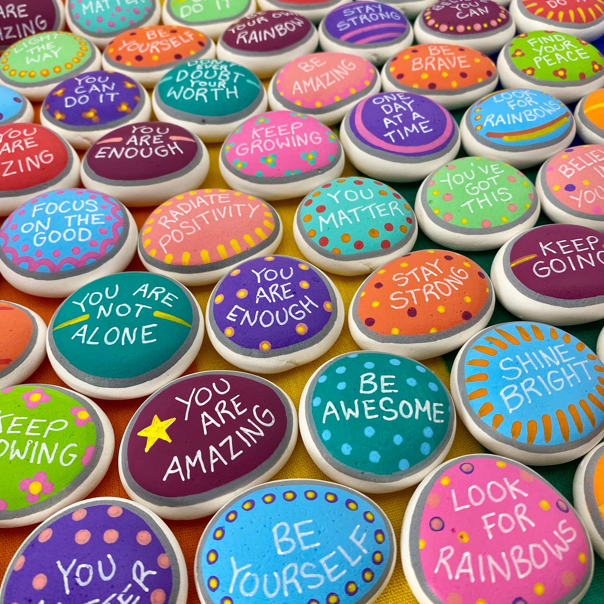 Lots of Colourful Hand painted pebbles with uplifting affirmations written on